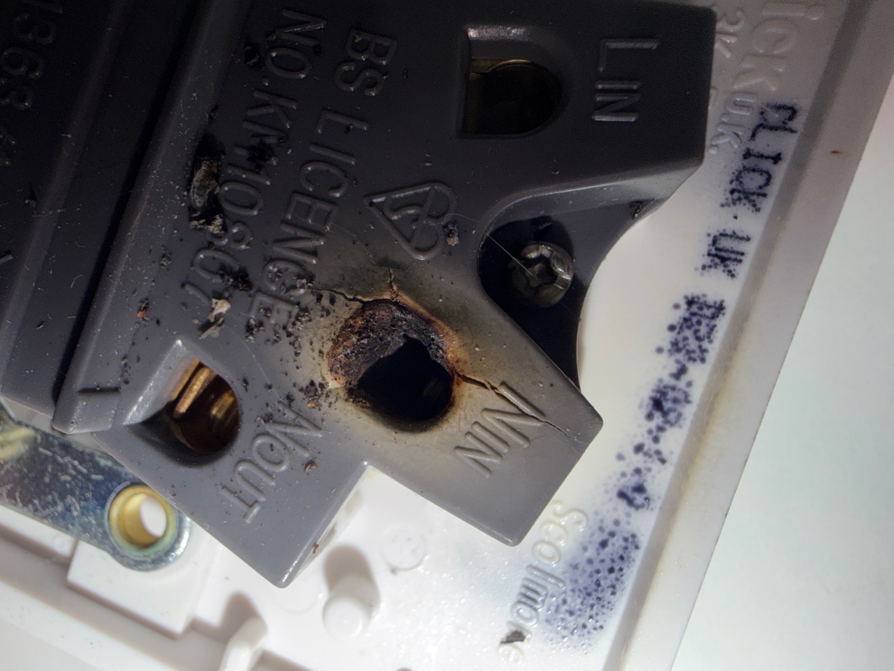 Macro of the N IN terminal — carbonised plastic, cracked housing and heat-eroded brass from sustained loose-connection arcing.